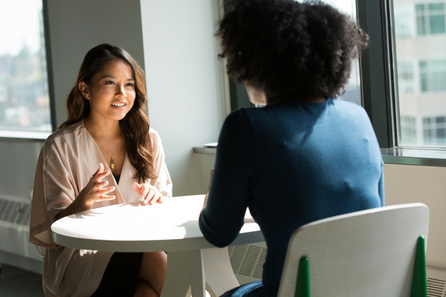 Two women in warm conversation across a sunlit table